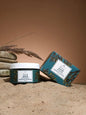 Firming algae body mask and packaging on sandy surface, showcasing organic skincare benefits.