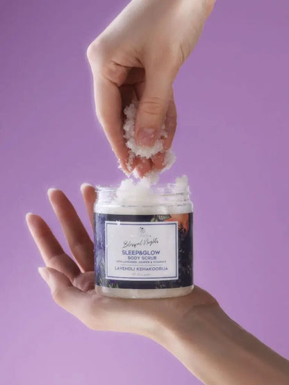 Hands holding a jar of Sleep&Glow Body Scrub with lavender and sea salt for organic skincare.